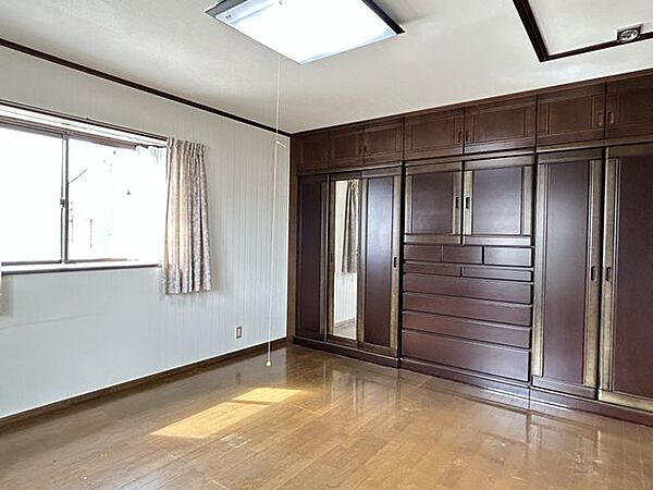 【洋室1】約10帖。壁一面に収納を備えた洋室です。衣類や荷物をすっきり収納でき、お部屋を広くお使いいただけます。