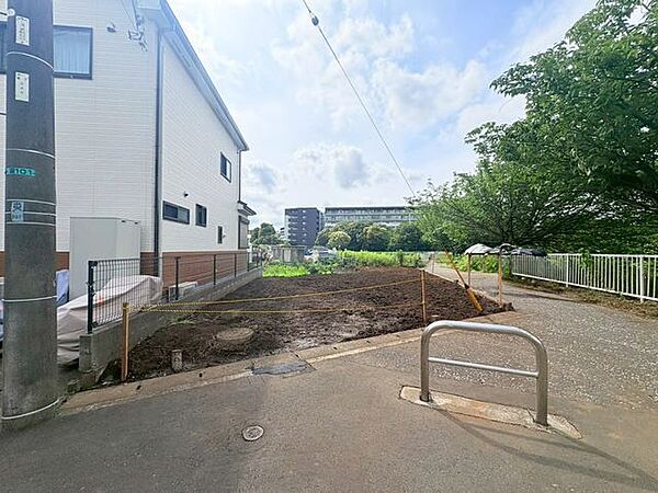 【前面道路】二方道路に面しているため、敷地全体に圧倒的な開放感と明るい陽光が届く現地外観。すっきりと整備されたアプローチが、日々の軽快なフットワークを便利にサポートします。