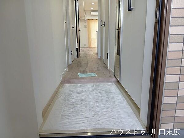居住空間へと続く、木目の質感が美しいフローリングを採用した廊下。段差を抑えた設計で、日々のスムーズな生活動線を確保します。