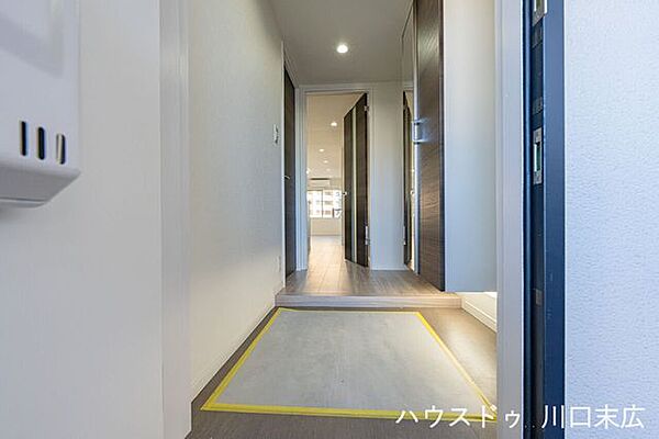 ダークブラウンの建具が落ち着きを演出する玄関アプローチ。段差を抑えた上がり框が帰宅時の安全な動線を確保。重厚感のあるドアが、住まいの第一印象を彩ります。