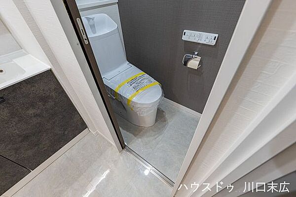 温水洗浄便座付きのトイレは、落ち着いた色調のアクセントクロスが印象的。壁付けリモコンで操作しやすく、手洗い一体型のため限られた空間をスッキリと有効に活用しています。