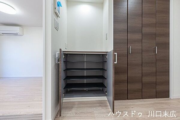 壁面と調和する木目調の扉付き収納。生活感を隠しながら、玄関からリビングへの動線上で必要な物をサッと取り出せます。上下に分かれた扉で、物の出し入れもスムーズです。