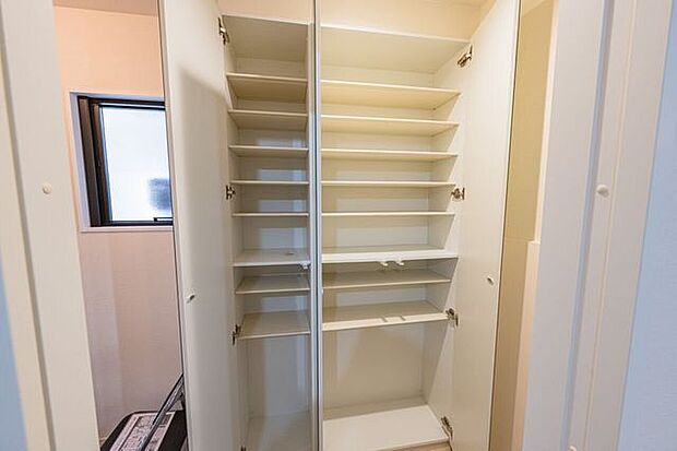 家族の靴を効率よく収める、可動棚仕様のシューズボックス。扉の大型ミラーが外出前の身だしなみをスマートに整え、玄関空間をより奥行きのある印象に仕立てます。