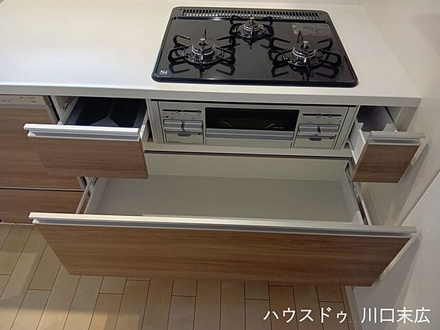 同時調理が可能な3口コンロと、調理器具をたっぷりとしまえるスライド収納を備え、機能的で美しいキッチン空間を実現しました。