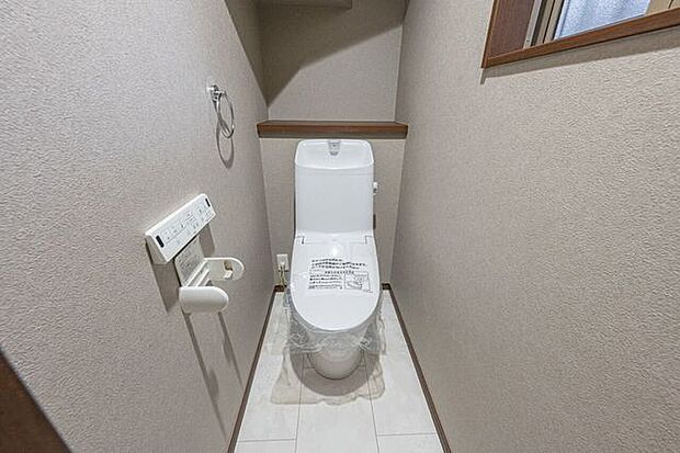 温水洗浄便座を備えた快適なレストルーム。上部の棚や手洗い付きのタンクなど、限られた空間を有効活用する工夫が施されています。