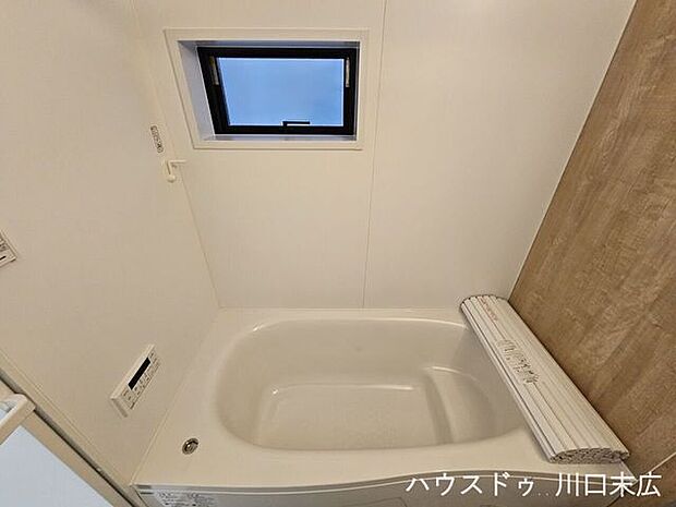 木目調のアクセントパネルが落ち着きを与えるバスルーム。足を伸ばして寛げる浴槽で、一日の疲れをゆっくりと癒やすことができます。