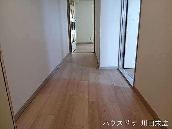 木目調のフローリングが奥へと続く動線。各居室を緩やかに繋ぎ、パブリックとプライベートな時間を切り替える役割を果たします。