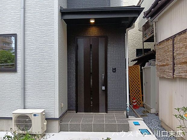 シックな色合いの玄関ドアが、住まいの顔として落ち着いた雰囲気を演出します。日々の出入りを支える機能的なアプローチです