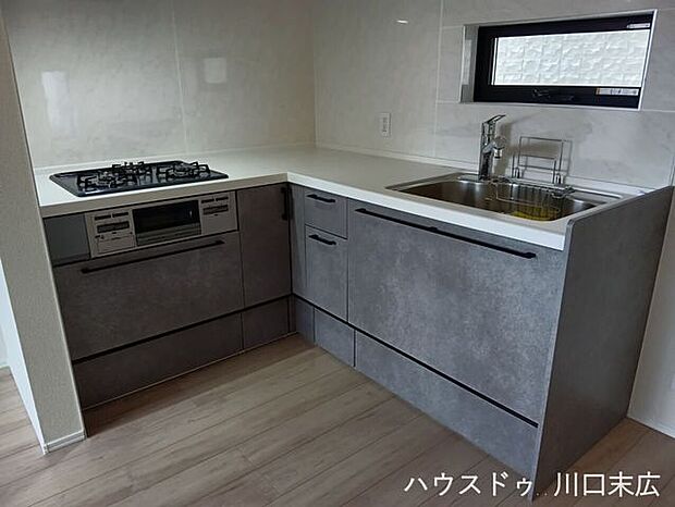 落ち着いたストーン調の面材が洗練された印象を与えるシステムキッチン。スライド式の収納で、調理器具の出し入れもスムーズです。