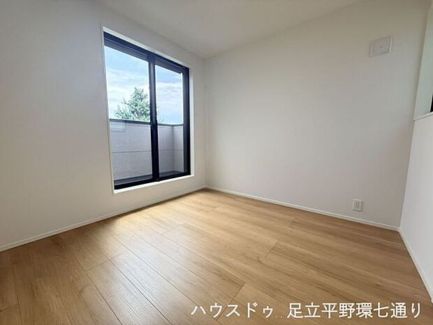 大きな窓から光が差し込む明るい洋室。バルコニーに面し、開放感のある心地よい空間です。