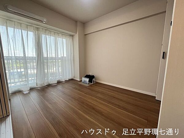 大きな窓から光が差し込む明るい洋室。バルコニーに面し、開放感のある心地よい空間です。