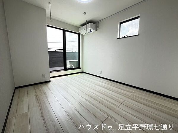大きな窓から陽光が差し込む明るい洋室。バルコニーに面しており、開放感のある快適な住空間です。