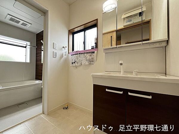 三面鏡付き洗面化粧台を備えた洗面室。収納スペースもあり、身支度用品をすっきり保管できます。