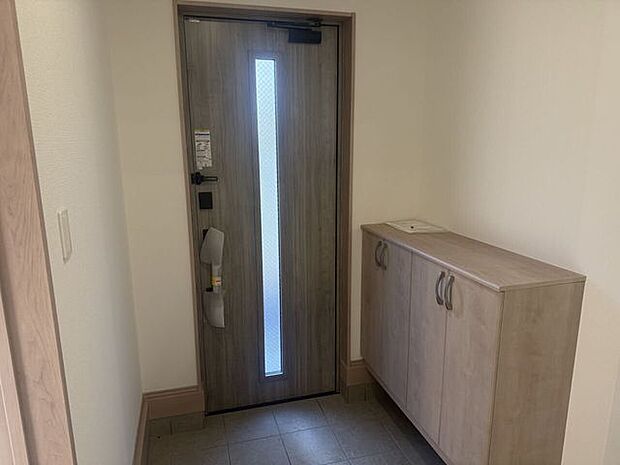 木目調の玄関ドアと収納付きシューズボックス。すっきり片付く玄関空間です。