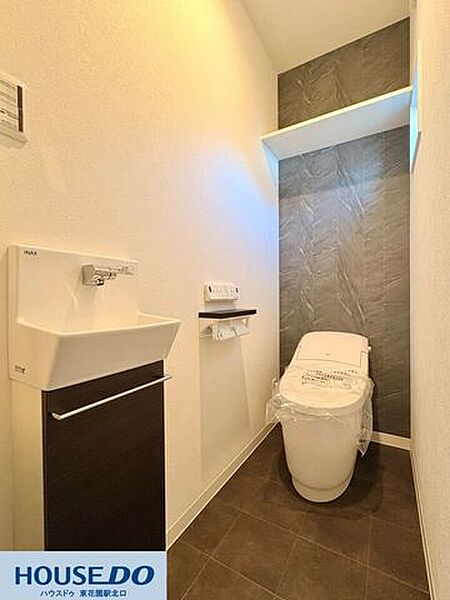 独立した手洗い場と収納棚を備えた、機能的なトイレ空間です♪ 温水洗浄便座は清潔感のあるデザインを採用！背面のアクセントクロスと、小物を置ける便利な棚が、実用性と心地よさを両立させています♪