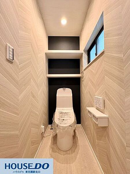 ヘリンボーン調の壁紙とブラックのアクセントが格好いい、デザイン性の高いトイレです！便利な収納棚が設置されているので、ストックや掃除用具もすっきり片付きますね♪窓からの自然光で明るい空間になっています！