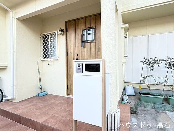 温かみのある木目調ドアとテラコッタ風タイルが迎える、お洒落な玄関アプローチ