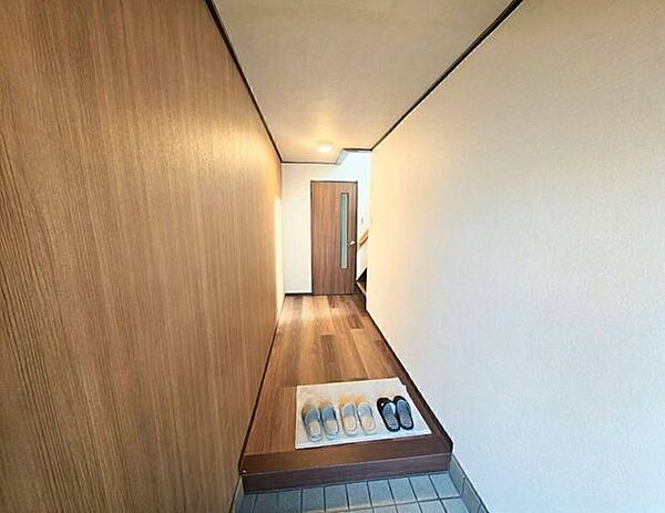 玄関から室内へまっすぐ伸びるすっきりとした廊下動線。奥には扉と階段が配置され、各部屋や上階への移動がスムーズです。靴の脱ぎ履きがしやすいゆとりある土間スペースも魅力です。