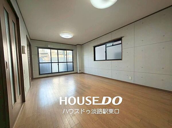 コンクリート打ちっぱなし調の壁面が目を引くスタイリッシュなリビング。温かみのある木目調フロアや落ち着いたドア枠がインダストリアルな内装と馴染み、洗練されたお洒落な空間を演出しています。