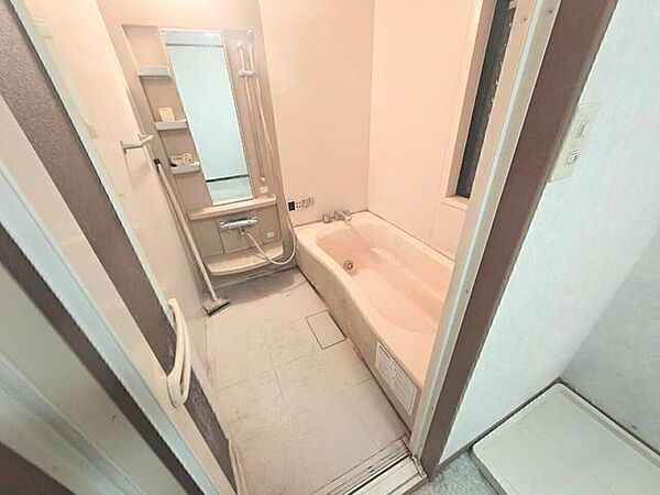 水はけに配慮された床面とシンプルな浴槽デザインで、日々の清掃がしやすい仕様です。コンパクトながらも手すりや鏡がしっかりと配置された安全性の高い設計です。（78文字）