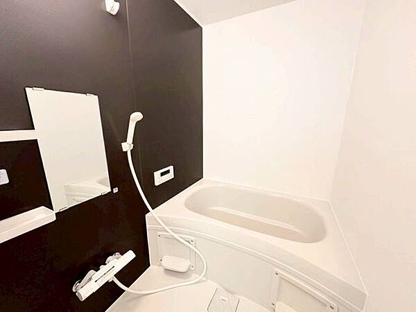 壁一面に配されたシックな黒のアクセントパネルと、白を基調とした壁・浴槽のコントラストが映えるモダンデザイン。空間を引き締める上質なインテリア構造が魅力です。