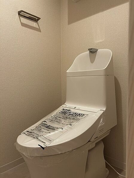 ベージュクロスが創り出す、温かみのあるクリーンなトイレ空間。 手洗い付きの新品一体型トイレとスタイリッシュな金属パーツが調和する、心地よいプライベートスペースです。
