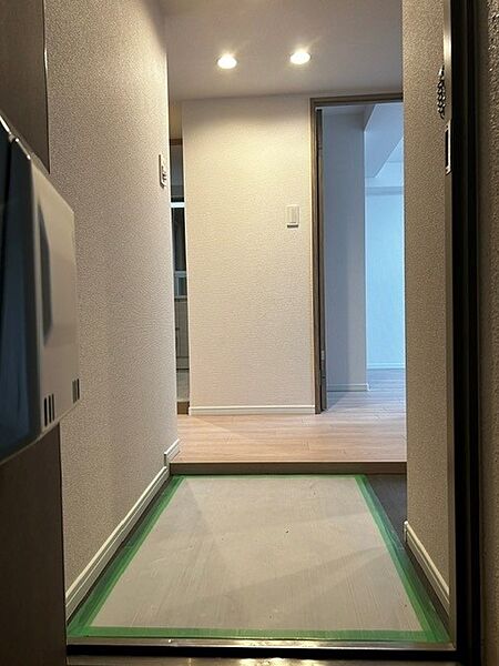 玄関口から室内へとまっすぐ視線が抜ける開放的な廊下設計！ナチュラルな木目調フロアと優しいダウンライトの灯りが温もりのある空間を演出。クリーンで心地よい住まいの顔となる玄関です。