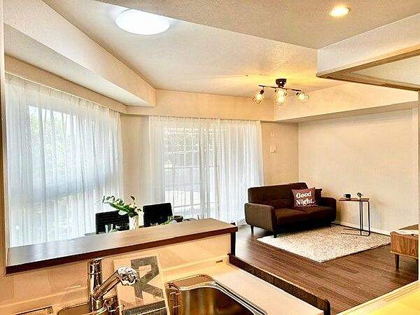 キッチンか 家事をしながらリビング全体や外の景観が見渡せる安心の対面レイアウト！2箇所の大きな窓から明るい自然光が差し込み、シックなデザイン照明がカフェのような寛ぎを演出する上質な住空間です。