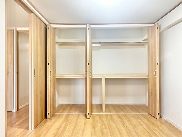 服も布団もスッキリ収まる機能的な壁一面大容量収納！ハンガーパイプと中段棚を備え、衣類から大型荷物まで効率よく整理できます。ナチュラルな木目が心地よい、片付け上手になれる快適居室空間です。