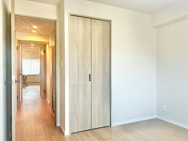 木目扉の折れ戸クローゼットを備えた清潔感あふれる洋室！白を基調とした壁面と温もりある木目フロアが洗練された空間を演出します。扉を開ければ廊下や他室へスムーズに繋がる、使い勝手の良い明るいお部屋です。