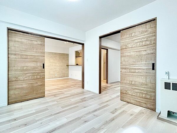 引き戸を開放することでLDKや隣室と繋がり、大空間としてフレキシブルに活用できる洋室！明るい木目調のドアとフローリングが開放感を高めます。暖房設備も整い、心地よく過ごせる快適なお部屋です。