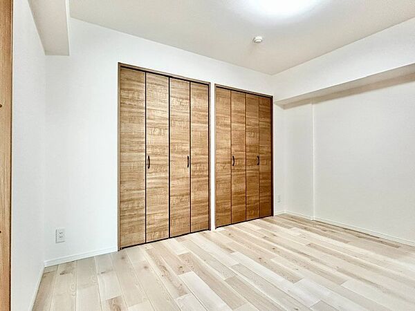 壁面に2並びの木目調大容量クローゼットを備えた洋室！衣類や季節の荷物もすっきり整頓でき、お部屋を広々と使えます。白基調の壁面と明るいフローリングが爽やかで清潔感あふれる居室空間を演出します。