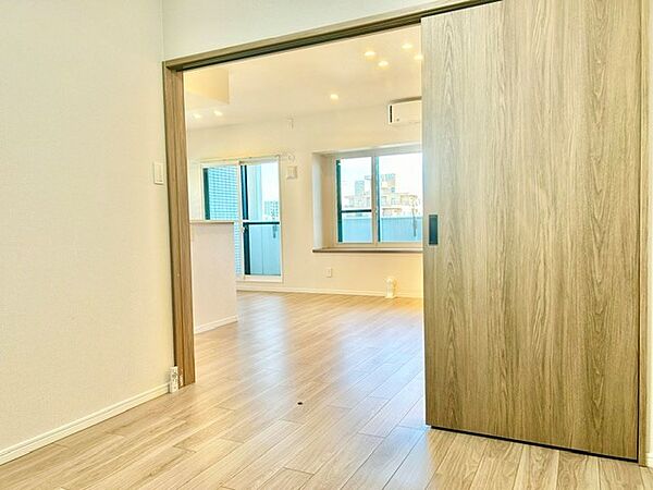 引き戸を開放すればLDKと一体となり大空間として活用できる洋室！用途に合わせて仕切り、個室としてもフレキシブルに使えます。ナチュラルな木目調扉と温もりある内装が、リビングと調和する快適な空間です。