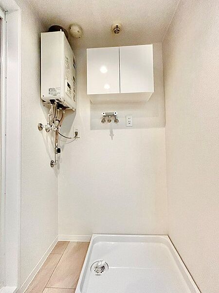 洗濯機置場の上に便利な吊戸棚を備えた機能的なスペース！洗剤やランドリー用品を上部にまとめて収納できるため、足元をすっきりと保てます。壁面やパンも清潔感あふれる白で統一された使いやすい設計です。