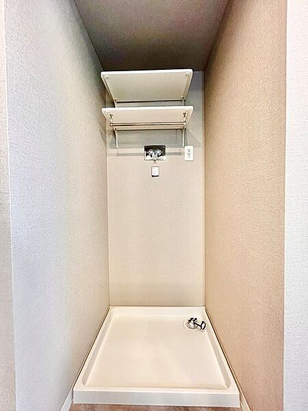 上部に2段の棚板を備えた使い勝手の良い洗濯機置場！洗剤や柔軟剤などのランドリー用品を手の届く位置に整理できます。防水パン付きで万一の水漏れにも配慮された、清潔感のある機能的なスペースです。