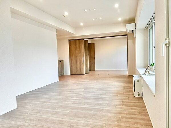 可動式引き戸を開放すれば隣室とつながる大空間！温もりある木目調フロアと上質なダウンライト、大きな出窓から光が届く明るいリビングです。扉の開閉で間取りを自在に変更でき、開放感あふれる暮しを叶えます。