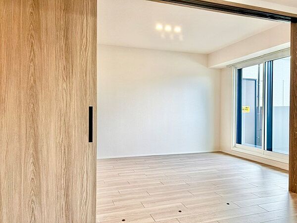 引き戸の開閉でリビングとスムーズに繋がるフレキシブルな洋室！大きな窓から明るい光が注ぎ、木の温もりを感じる心地よい空間です。個室としても大空間の一部としても使える、自由度の高い魅力的な一室です。