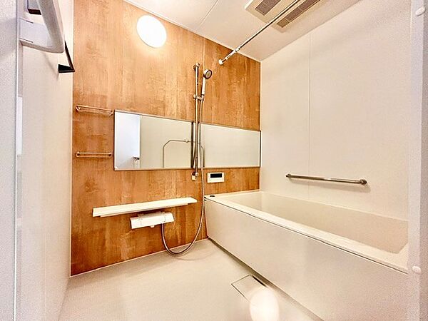 木目調のアレセントパネルが高級感を演出する、スタイリッシュなバスルーム！ワイドな鏡が空間を広く見せ、快適なバスタイムを叶えます。浴室乾燥機や手すり、ランドリーパイプも備わった充実の機能性が魅力です。