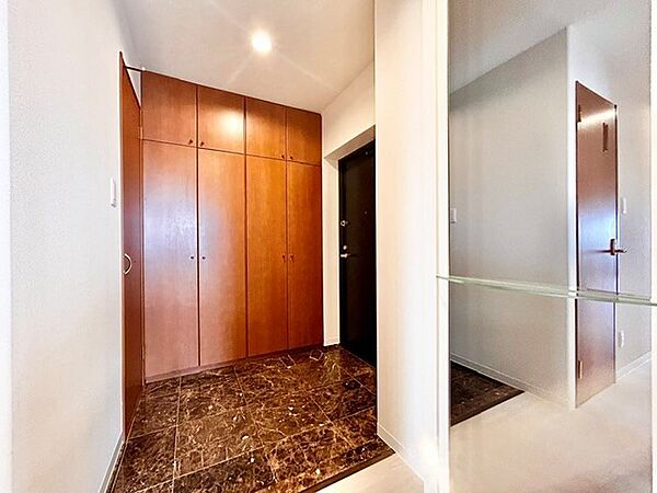 重厚感ある大理石調の土間タイルと大容量の木目調シューズボックスが印象的な玄関。お出かけ前の身だしなみチェックができる大きな全身鏡を配置し、機能性と上質な雰囲気を併せ持った魅力的な空間です。