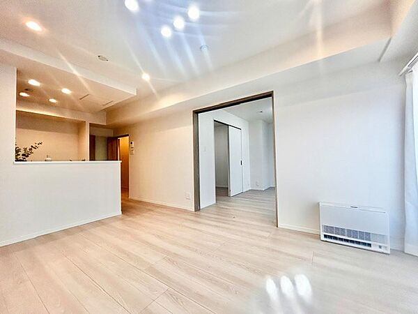 対面キッチンから全体が見渡せる開放的なリビング！隣接する洋室の引き戸を開ければ、より広がりのある空間として利用できます。ダウンライトの優しい灯りと明るい木目調フロアが魅力を添える上質な居室です。