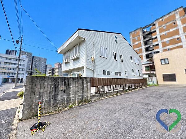 《建物外観》建物側面には塀やフェンスが設けられており、敷地の奥行きや隣地との位置関係も確認できます。落ち着いた色合いの外観が周辺の街並みに調和しています。
