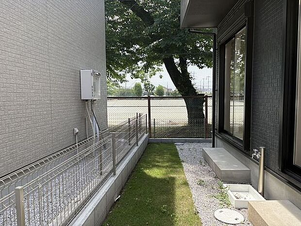 リビングから出入りできる、青々とした芝生が心地よい専用庭。外水栓が備わっているため、ガーデニングやプール遊び、靴の汚れ落としもスムーズです。奥に見える豊かな木々が、日々の暮らしを穏やかに彩ります。