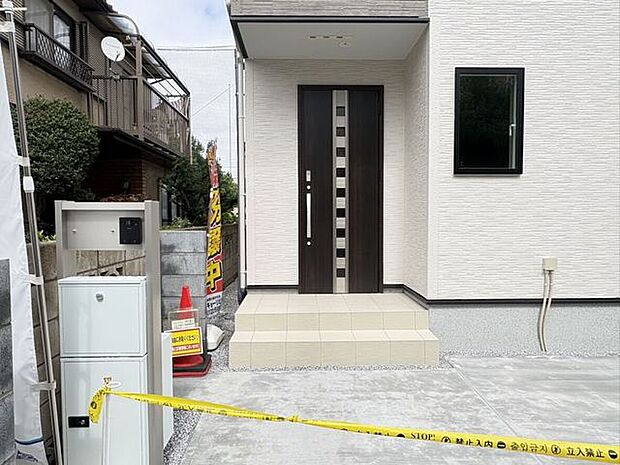 落ち着いた色合いの玄関ドアが、白い外壁に映えるモダンな佇まいです。足元は段差の少ない設計で、お子様連れのお出かけや買い物の帰りもスムーズに。家族を温かく迎え入れてくれる、やさしい雰囲気の住まいです。
