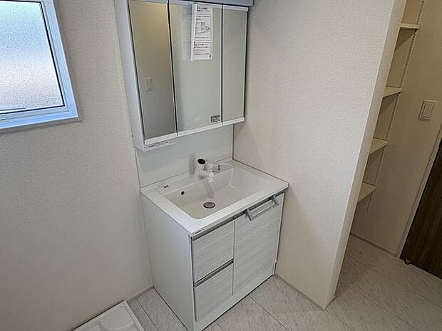 洗面脱衣所には三面鏡付きの洗面化粧台を配置しており、忙しい朝の身支度も効率的です。床面には水汚れに強い素材を採用しているため、日々のお掃除も簡単で、いつも清潔な空間を保つことができます。