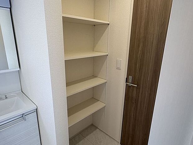 洗面所横に備え付けの可動棚があり、タオルや洗剤のストックをすっきりと整理できます。家事動線がスムーズになり、毎日の身支度も心地よい時間に変わります。