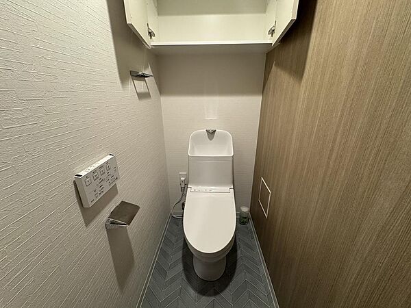 シンプルで清潔感のあるトイレに収納棚を備え、トイレットペーパーや小物もすっきり整理できる使いやすい空間です。