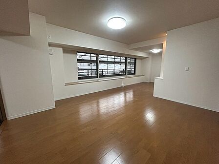 木目の床と白い壁でまとめた、落ち着いた雰囲気のリビング。横長の窓が空間に広がりを添えます。ソファやダイニングテーブルの配置を考えながら、家族が集う時間や日々の過ごし方まで現地でイメージできる空間です。