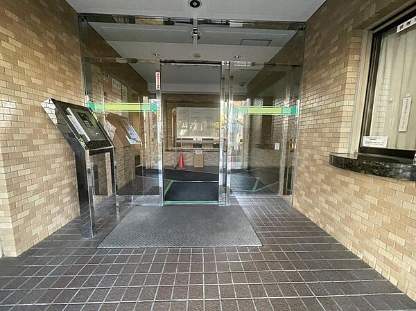タイル張りの壁とガラス扉が迎えるエントランス。落ち着いた雰囲気の共用空間に、オートロック設備を備えています。外から室内への動線や扉の開閉、荷物を持った際の出入りのしやすさも、見学時に確認してください。