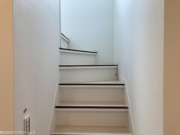 白を基調とした壁と階段に、濃い茶色の手すりや蹴込み板のラインがアクセントとして入っており、シンプルでモダンなデザインです。