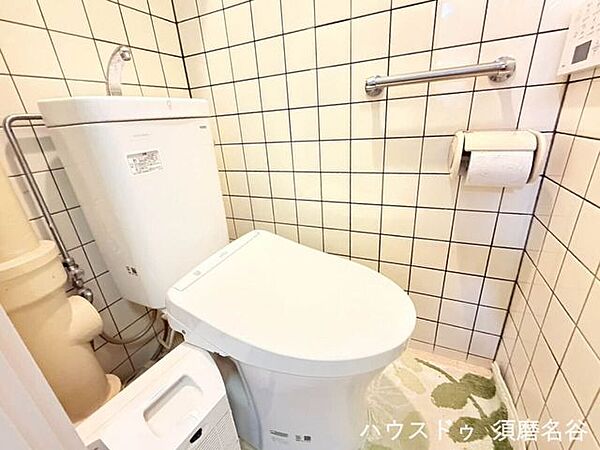 壁面にしっかりとした手すりが設置された、安全性に配慮されたトイレスペース。ペーパーホルダー上部には小物を置ける便利な棚もあり、快適に使用できます。